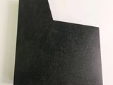 a close up of a piece of black paper on a white surface
