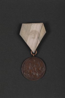 an old medal with a ribbon around it on a black surface