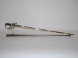 une cuillère en argent et une paire de ciseaux posés sur une surface blanche