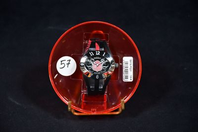 une montre rouge dans un étui en plastique posé sur une surface noire