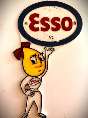 un panneau sur lequel est inscrit « Esso », avec un personnage de dessin animé tenant une pancarte