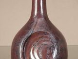 a red vase sitting on a table with a light on top of it