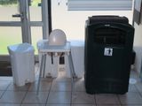une poubelle noire et une chaise haute blanche dans une pièce