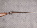 Le fusil est posé par terre, près du mur.