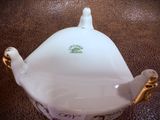 a white teapot with a gold handle on a table