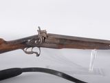 un vieux fusil avec un canon en bois et une sangle noire