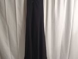 a black dress hanging on a hanger in front of a white curtain