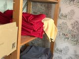 a wooden shelf filled with lots of clothes and boxes