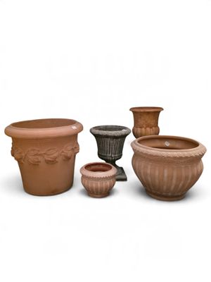 quatre pots en terre cuite posés les uns à côté des autres sur une surface blanche