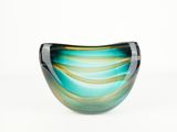 un bol en verre bleu et vert posé sur une surface blanche