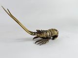 un gros plan d'une statue en laiton représentant un homard sur fond blanc