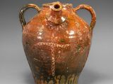 un vase marron muni d'anses, sur un fond gris