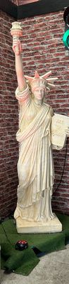a statue of the statue of liberty in front of a brick wall