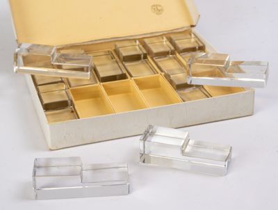une boîte argentée remplie de récipients en plastique transparent, posée sur une surface blanche
