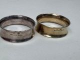 two silver wedding rings with engraved names on them sitting on a table