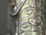 a silver vase that has a leaf design on it
