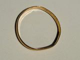 une bague en or posée sur une surface blanche, sur fond blanc