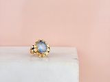une bague en or sertie d'une pierre bleue, posée sur un bloc de marbre