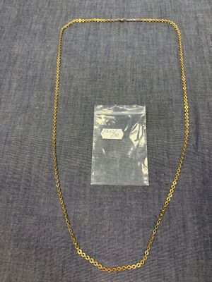 un collier à chaîne en or, avec un sac en plastique transparent en arrière-plan