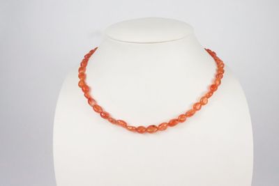 un collier composé de perles de cornaline sur un mannequin blanc