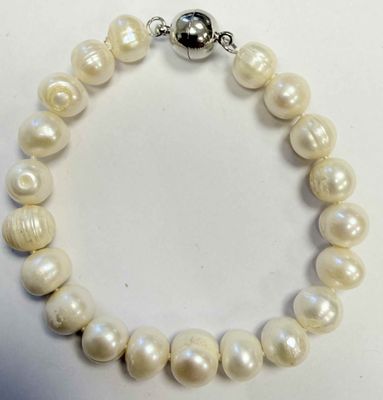 un gros plan d'un bracelet de perles blanches posé sur une surface blanche