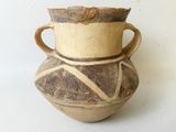 un vase marron muni d'une anse marron, posé sur une table blanche