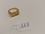 une bague en or à laquelle est attachée une plaque portant un nom