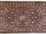 Un tapis persan ancien est exposé sur un fond blanc.