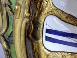 close up of a clock with a gold frame and blue and white stripes