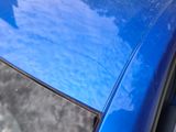 a close up of a blue car ' s hood and window