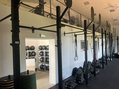 une photo d'une salle de sport avec une rangée d'haltères