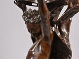 bronze statue of a man holding a bottle in his hand