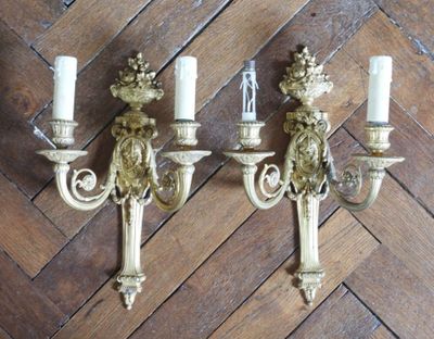 two wall sconces that are on a wooden floor