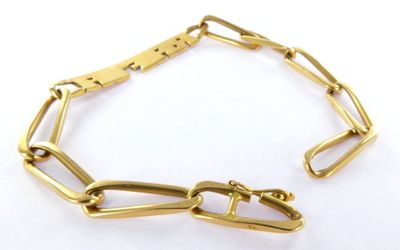 a close up of a gold chain bracelet on a white surface