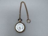 une montre de poche ancienne à laquelle est accrochée une chaîne sur le côté