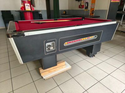 une table de billard recouverte d'un tapis rouge dans une pièce