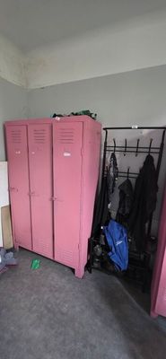a pink locker in the corner of a room next to a bed