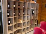 Des bouteilles de vin sont rangées sur des étagères dans une cave à vin où se trouvent des chaises rouges