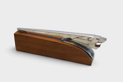 a silver stapler on a wooden stand on a white background