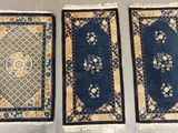 three oriental rugs are lined up on a table