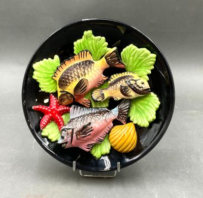 un saladier noir rempli de poisson et de légumes posé sur une table