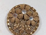 an image of a gold brooch with pearls on a white surface