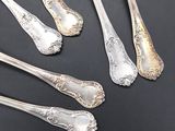 five silver spoons and two silver spoons on a black surface