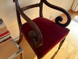 a red chair sitting in a room next to a book shelf