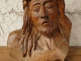 a wooden bust of jesus on a shelf with a white wall in the background