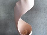 une sculpture blanche posée sur une table en bois, avec un tableau accroché au mur derrière elle