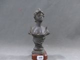 un buste en bronze représentant une femme, posé sur un socle en bois