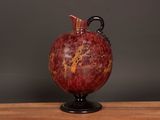a red vase sitting on top of a wooden table