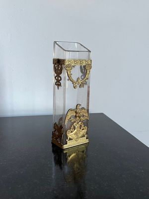 un vase en verre avec une horloge posé sur une table