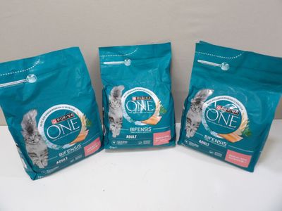 trois sacs de nourriture pour chat posés sur une table